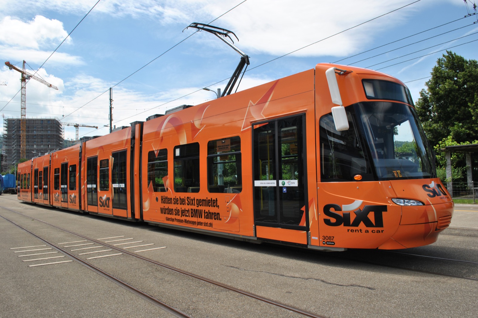 Oranges Tram mit vollflächiger Sixt-Werbung in Zürich